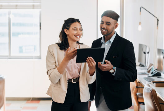 Have a look at this. Shot of two young businesspeople standing in the office together and using a digital tablet.