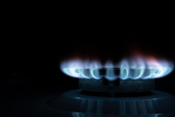 Gas burner with blue flame, glowing fire ring on kitchen stove.Concept of gas crisis. High prices of natural resources. Tongues of flame. Public debt. Energy war. Saving home budget.