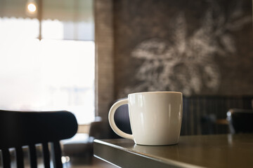 The white coffee mug on the table and the background of the wall has a blurry pattern that resembles the smoke of heat.