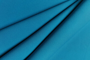 Blue crumpled or wavy fabric texture background. Abstract linen cloth soft waves. Gabardine wool fabric. Merino yarn. Smooth elegant luxury cloth texture. Concept for banner or advertisement.