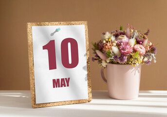 may 10. 10th day of month, calendar date.Bouquet of dead wood in pink mug on desktop.Cork board...