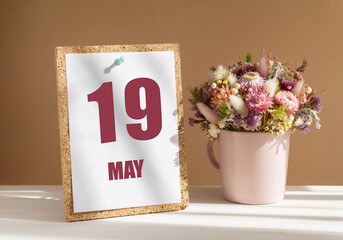 may 19. 19th day of month, calendar date.Bouquet of dead wood in pink mug on desktop.Cork board with calendar sheet on white-beige background. Concept of day of year, time planner, spring month