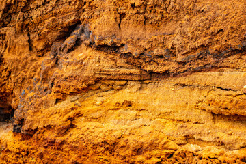 Fototapeta premium Textural sand, with relief surface, multi-colored layers and different in size of granules, in outdoor sand career, after mining ore and sand for construction.