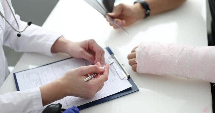Doctor conducts medical consultation with patient with plaster on arm