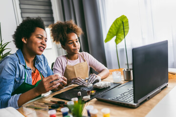 Mother and daughter spend time together and sculpting from clay at home watching online lessons