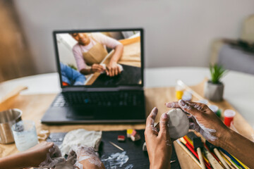 Mother and daughter spend time together and sculpting from clay at home watching online lessons
