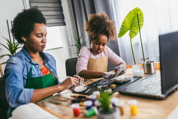 Mother and daughter spend time together and sculpting from clay at home watching online lessons