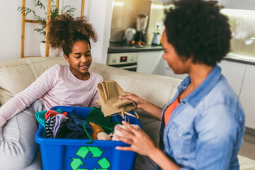 Mother and daughter sorting out clothes in boxes to donate or recycle at home