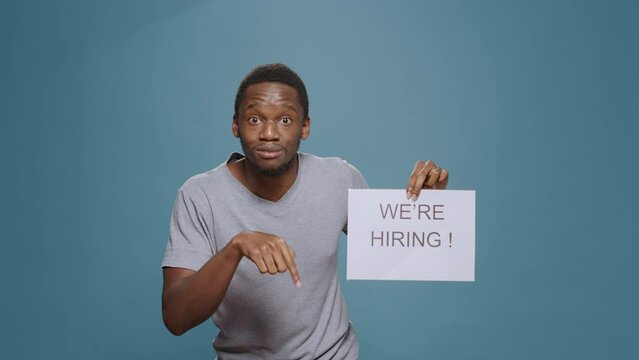 Company employee showing hiring application sign on paper, advertising job offer and career opportunity to hire candidate. Office worker preparing for interview with applicant, HR recruitment.