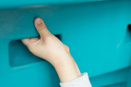 Child's hand holding in a turquoise wall while climbing indoor