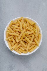 Penne pasta. Raw italian penne pasta on gray stone background