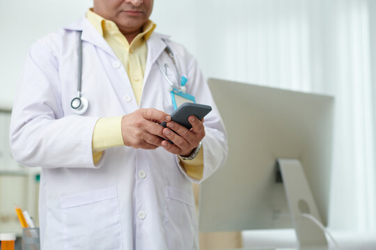 Cropped image of physician answering text messages from patient on smartph