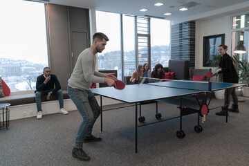 Young start up business man and woman playing table tennis at modern creative office space people group have meeting and brainstorming in background - obrazy, fototapety, plakaty
