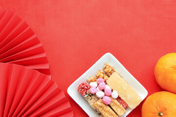 Chinese new year festival decorations. set of chinese sweetmeat, snacks and candies for chinese new year, fresh orange with red hand paper fan on red background.
