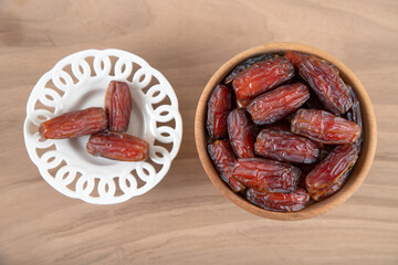 Bowl of dates fruit on wooden background, top view	