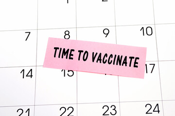 The phrase Time to Vaccinate written on a pink sticky note posted on a calendar or planner page. Deadline concept read a reminder on calendar date