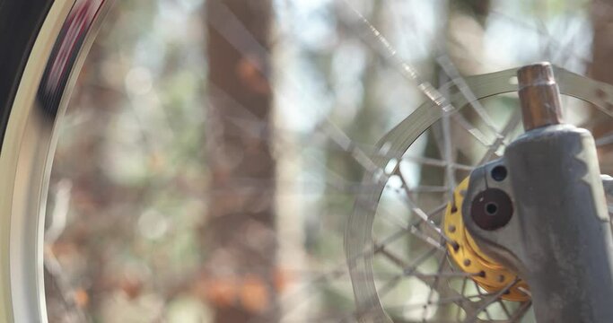 Mountain bike wheel spinning freely while upside down. Close up shot, shallow depth of field. Forest trees and vegetation background, sunny day, real time, no people