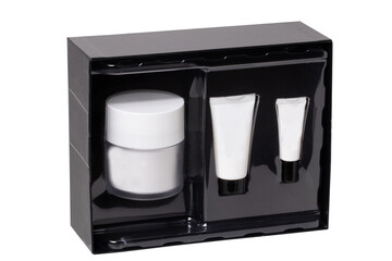 Obraz premium Closeup of a opened decorative black cosmetic box or gift box with label-free white tubes and containers isolated on a white background. Macro.