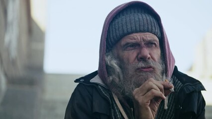 Depressed homeless elderly man smoking cigarette outdoor, poverty and crisis