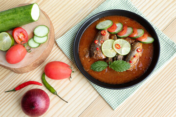 Spicy canned sardine salad, Delicious salad canned fish in tomato sauce with chili pepper, lemon, cucumber, tomato and fresh mint on wooden table.Thai food style homemade.