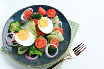 Fresh healthy  salad with boiled eggs, fresh cucumber slices,  broccoli, tomatoes and red onions in green plate. clean eating concept.