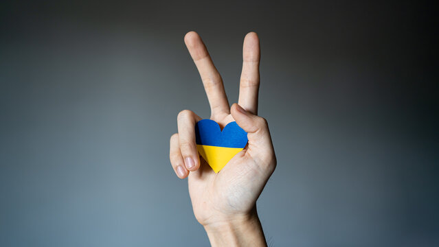 Ukraine flag color heart in hand making V sign