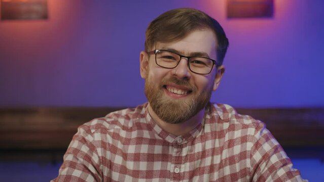 Portrait ukrainian young man in glasses indoor. Man looks in to the camera and laughs.