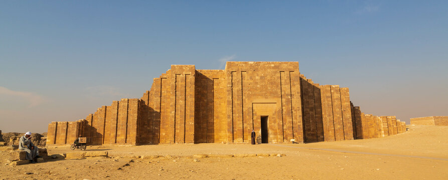 Saqqara, Cairo, Egypt - January 2022: Local man sitting in from of the Entrance to the Columnal Hall of Saqqara