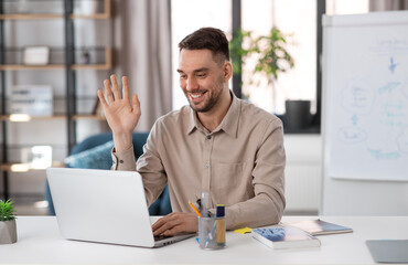 Naklejka premium distant education, school and remote job concept - happy smiling male teacher with laptop computer having online class at home office and waving hand