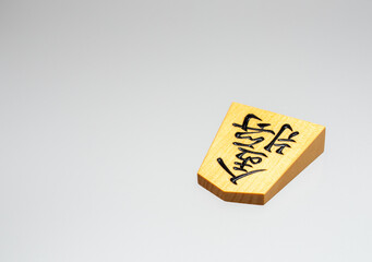 金色に輝く将棋駒（金将）を白バックで写したシンプルな将棋のイメージ写真