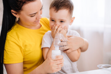 A child cries when inhaled with a nebulizer. A child with a viral disease in an inhalation mask is sitting in his mother's arms. Patient with asthma
