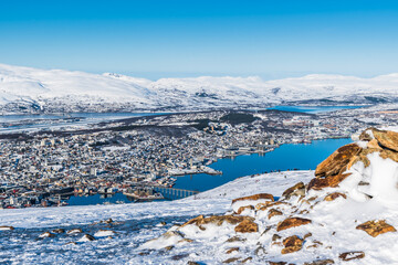 View to Tromso city in Norway from Storsteinen peak, a mountain ledge about 420 m (1378 ft) above sea-level, on a sunny winter day