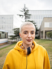 Young Caucasian woman with short hair looking at camera on a university campus. 