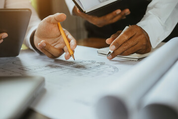 Businessman working as a team discussing data working and tablet, laptop with on on architectural project at construction site at desk in office.