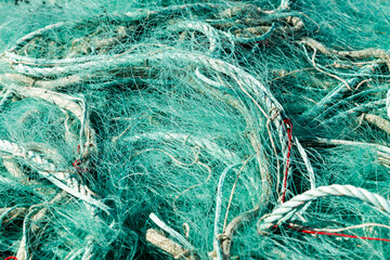 Filet de pêche en nylon vert rangé en tas dans un bac au retour de la pêche en mer.