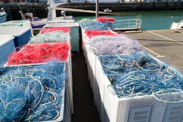 Filets de pêche en nylon coloré rangés en tas dans des bacs sur un quai, au retour de la pêche...
