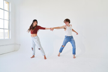 couple dancing in streetwear in white room 