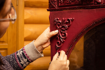 Woman with glasses attaching new carved beautiful wooden ornaments to red cardboard in workshop for...