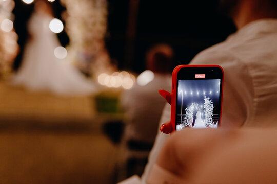  People using a smartphone take pictures during the wedding evening ceremony in the garden.