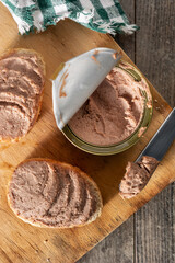 Dipping toasted bread with pork liver pate on wooden table