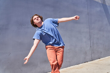 Man leaning dancing in front of gray blue wall