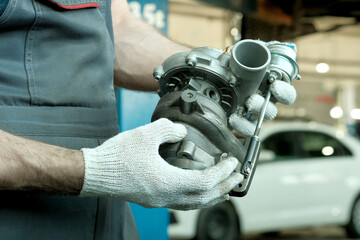 Repair and maintenance in the car center. An auto mechanic holds a turbine in his hands. Inspection...