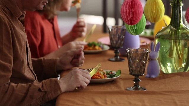Grandpa and grandma eating at Easter dinner sitting at the table at home