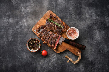 Grilled top sirloin or cup rump beef meat steak on wooden board. Dark background. Picanha steak
