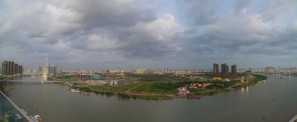 Naklejka premium Aerial view of Bitexco Tower, buildings, roads, Thu Thiem 2 bridge and Saigon river in Ho Chi Minh city - Far away is Landmark 81 skyscrapper. This city is a popular tourist destination of Vietnam