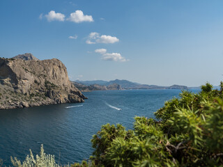 Naklejka premium View of the sea and neighboring mountains from the cape of the mountain. Seascape. Mountain landscape. Looking out at the sea among the bushes. Yachts and boats sail on the sea. Beautiful landscape.