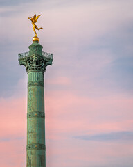 Front view of the Column of Jules in Paris while the pink sunset takes place in the background.