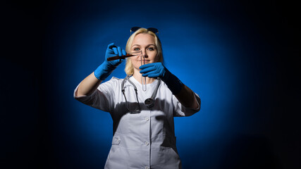 A female doctor in a white coat and gloves pours blood into a test tube on a dark background, hard light. The concept of laboratory research under sanctions.