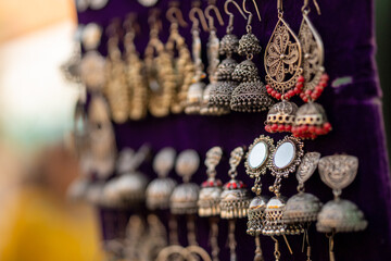 Indian-styled silver earrings handing on a velour board.