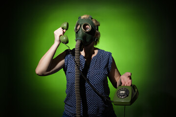 woman in a gas mask talking on a retro phone on a dark dramatic background, hard light